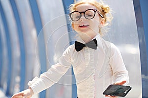 Little cute girl in glasses holds black cell phone