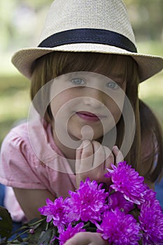 Little cute girl in a hat holding a bouquet of flowers