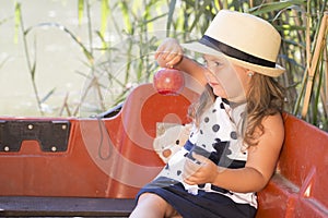 Little cute little girl with a hat sits in a boat on the lake an