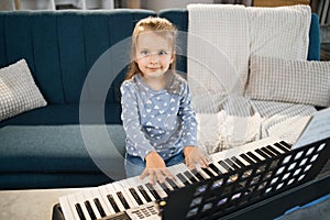 Little cute girl having lesson at piano at school of music.