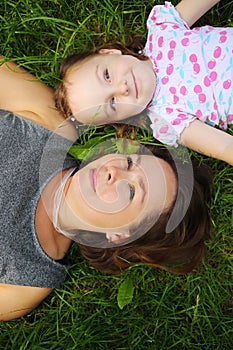 Little cute girl and her mother lie on grass and photo