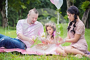 Girl with her parent sitting in park and watching flower