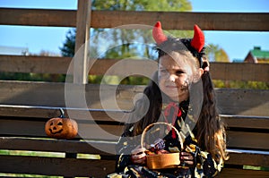 little cute girl in the image devil on Halloween. red horns on the head with black grimm for halloween zombie
