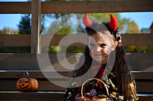 little cute girl in the image devil on Halloween. red horns on the head with black grimm for halloween zombie