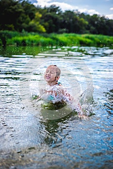 Little cute girl jumping off the dock into a beautiful river at