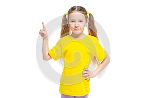 Little cute girl keeps pointing her finger at copy space. Isolated on white background.