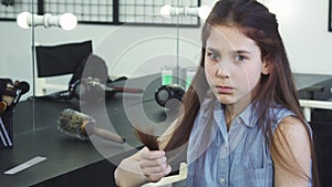 Little cute girl looking sad examining her damaged hair with split ends