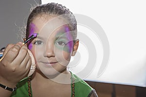 Little cute girl making facepaint before halloween party