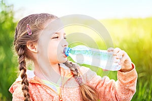 Little cute girl on the nature drinks water