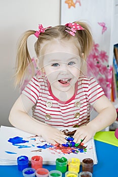 Little cute girl paints with fingers