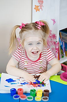 Little cute girl paints with fingers