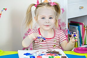 Little cute girl paints with fingers