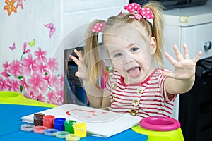 Little cute girl paints with fingers