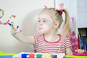 Little cute girl paints with fingers