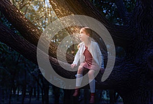 Little cute girl with pigtails sits on a huge tree at night. Magic fireflies at night
