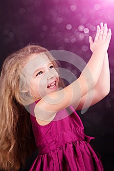Little cute girl in a pink dress on a black background
