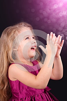 Little cute girl in a pink dress on a black background