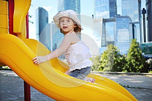 Little cute girl at plastic slide at playground