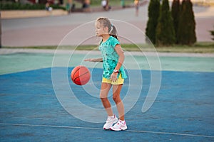 Little cute girl playing basketball outdoors