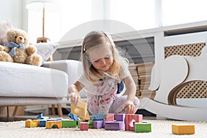 Little cute girl playing block toys in playroom at home.