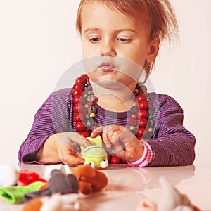 Little cute girl playing indoors with colored toys developmen