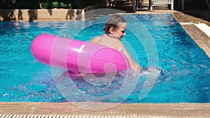 Little cute girl playing with pink inflatable ring in swimming pool. Summer travel hotel vacation