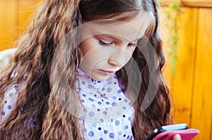 little cute girl playing with a smartphone, daylight, at home