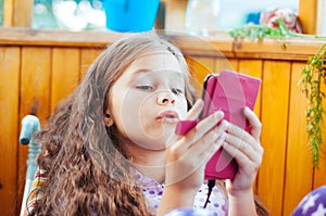 little cute girl playing with a smartphone, daylight, at home