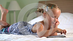 Little cute girl plays a game on the tablet