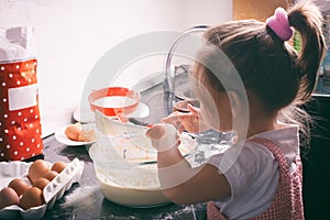 A little cute girl preparing the dough in the kitchen at home
