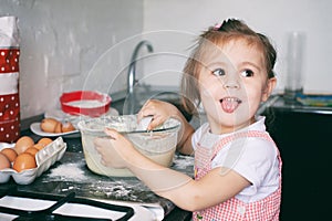 A little cute girl preparing the dough in the kitchen at home