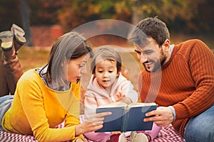 Little cute girl reading book her parents