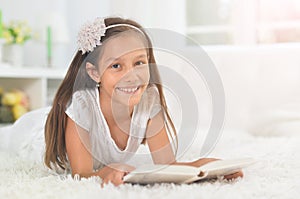 Little cute girl reading book at home