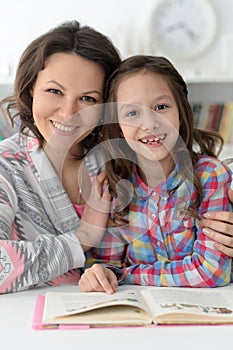 Little cute girl reading book with mother