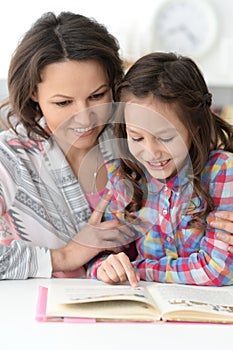 Little cute girl reading book with mother