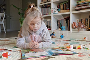 Little cute girl reading a book in the room, soft focus background. Education at home