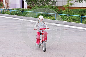 Little cute girl rides bicycle on parking