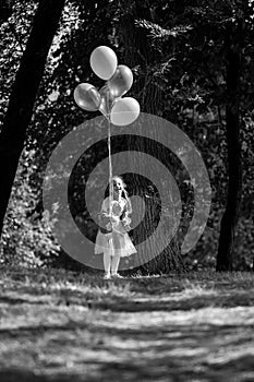 Little cute girl running in the Park with a bunch of balloons. She laughs provocatively. The concept of a happy childhood