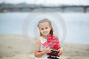 Little cute girl and scarlet sails. Close-up portrait of the girl`s face. little girl wait boat with scarlet sail. Summer day. Hap