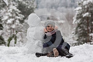 Little cute girl sculpts snowman. Winter.