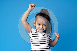 Little cute girl showing her strength on blue background