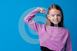 Little cute girl showing her strength on blue background