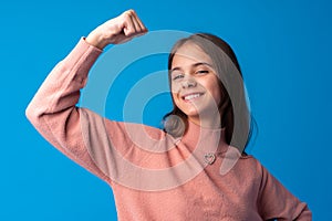 Little cute girl showing her strength on blue background