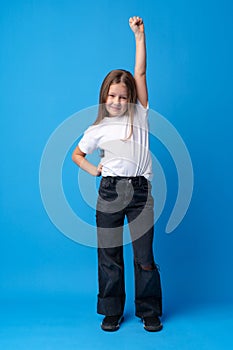 Little cute girl showing her strength on blue background