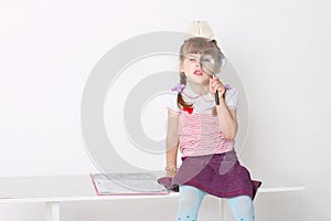 Little cute girl sits on bench with book