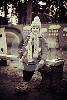 Little cute girl sitting on the bench in winter time. Monochrome