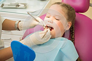 Little cute girl sitting in chair at dentist clinic during dental checkup and treatment, closeup portrait.