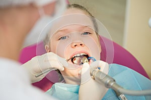 Little cute girl sitting in chair at dentist clinic during dental checkup and treatment, closeup portrait.