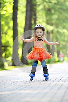 Little cute girl in skirt and helmet roller skates