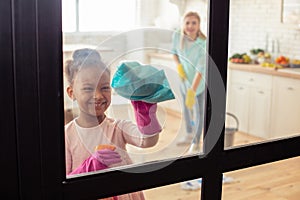 Little cute girl smiling while helping her mother with cleaning